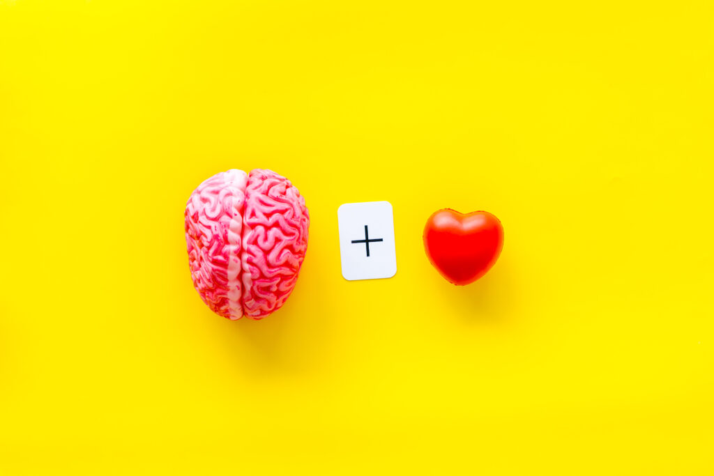 Gefühle und Geist Konzept mit Gehirn plus Herz auf gelbem Hintergrund Ansicht von oben