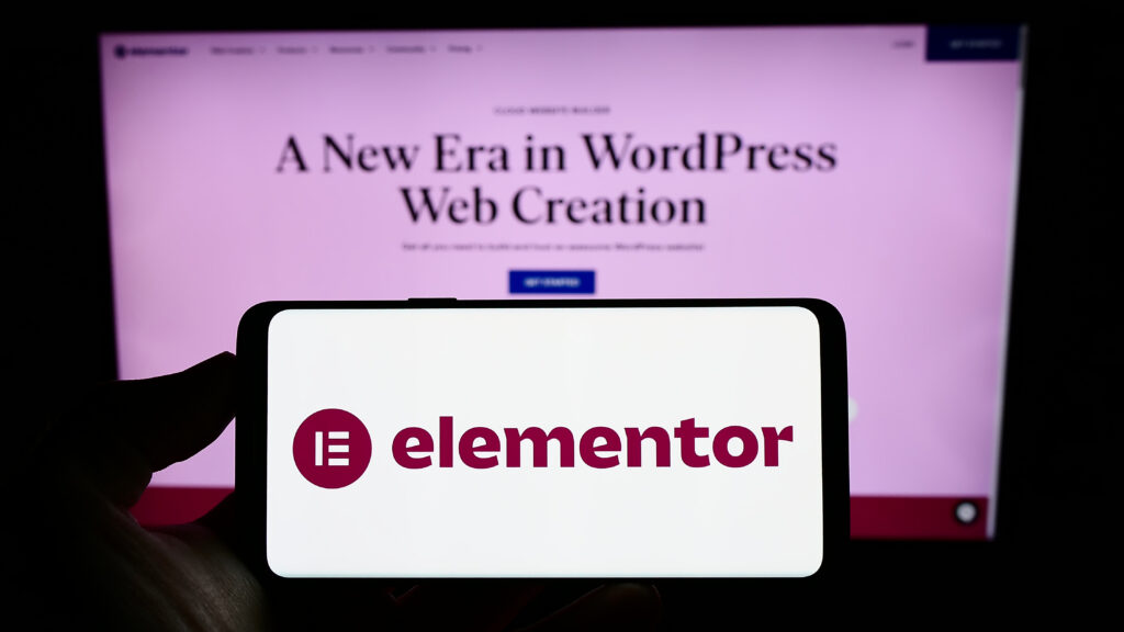 Person holding cellphone with logo of Israeli software company Elementor Ltd. on screen in front of business webpage. Focus on phone display.