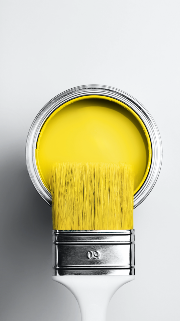 Pinsel Farbe gelb Anstrich Farbdose steht auf hellgrauer Flaeche Blick von oben
