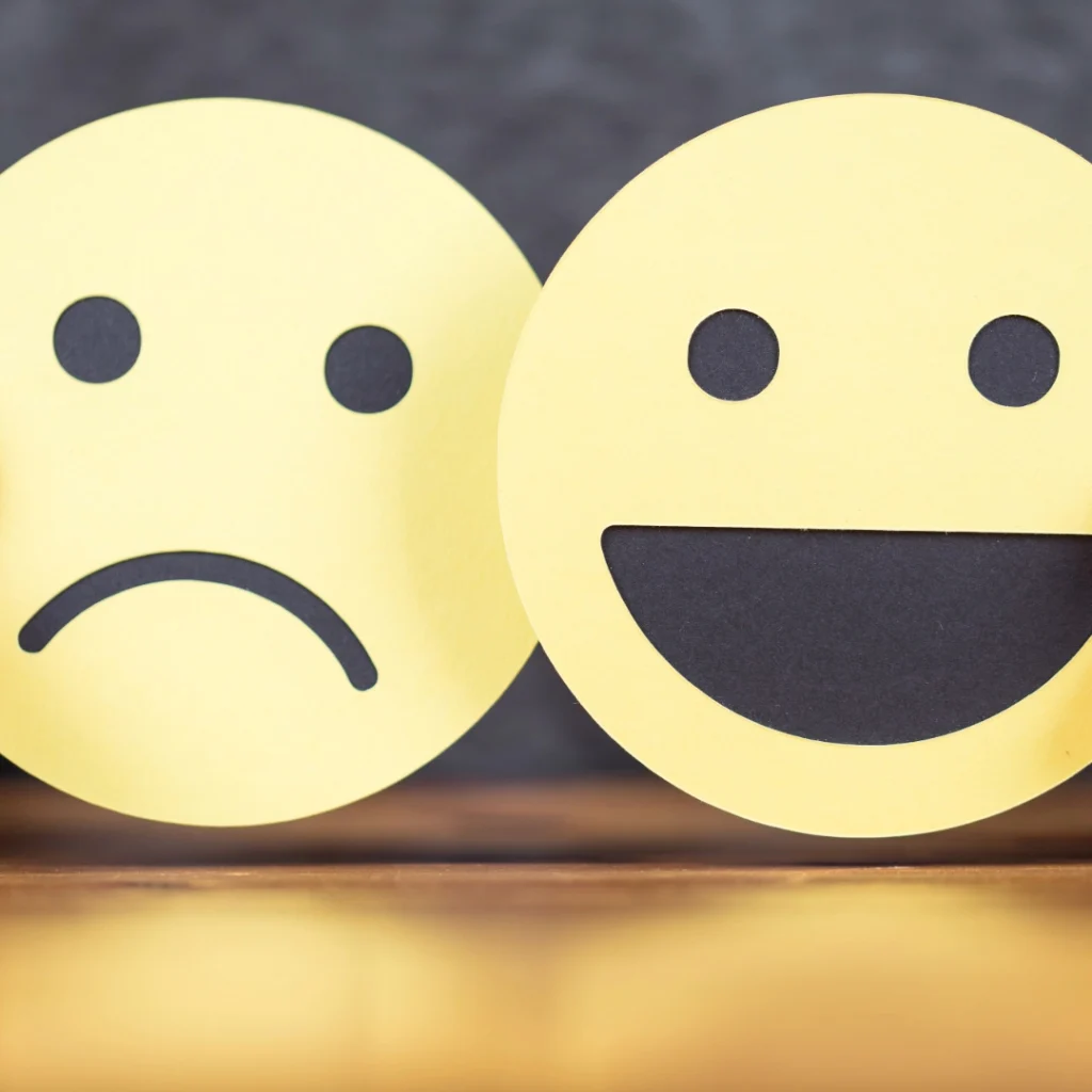 Zwei Holzplättchen mit Smiley- und Trauergesicht