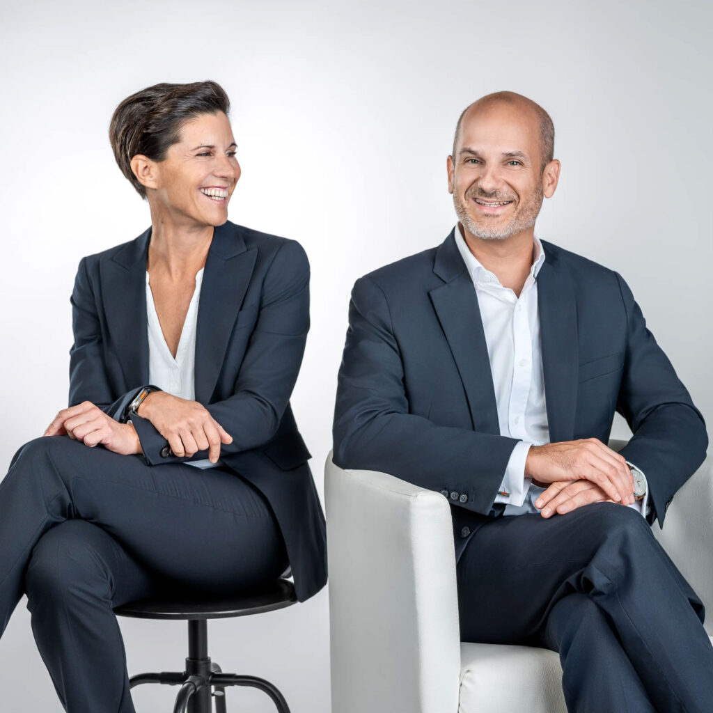 Rechtsanwälte Teamfoto, professionell gekleidet, gemeinsam sitzend vor neutralem Hintergrund