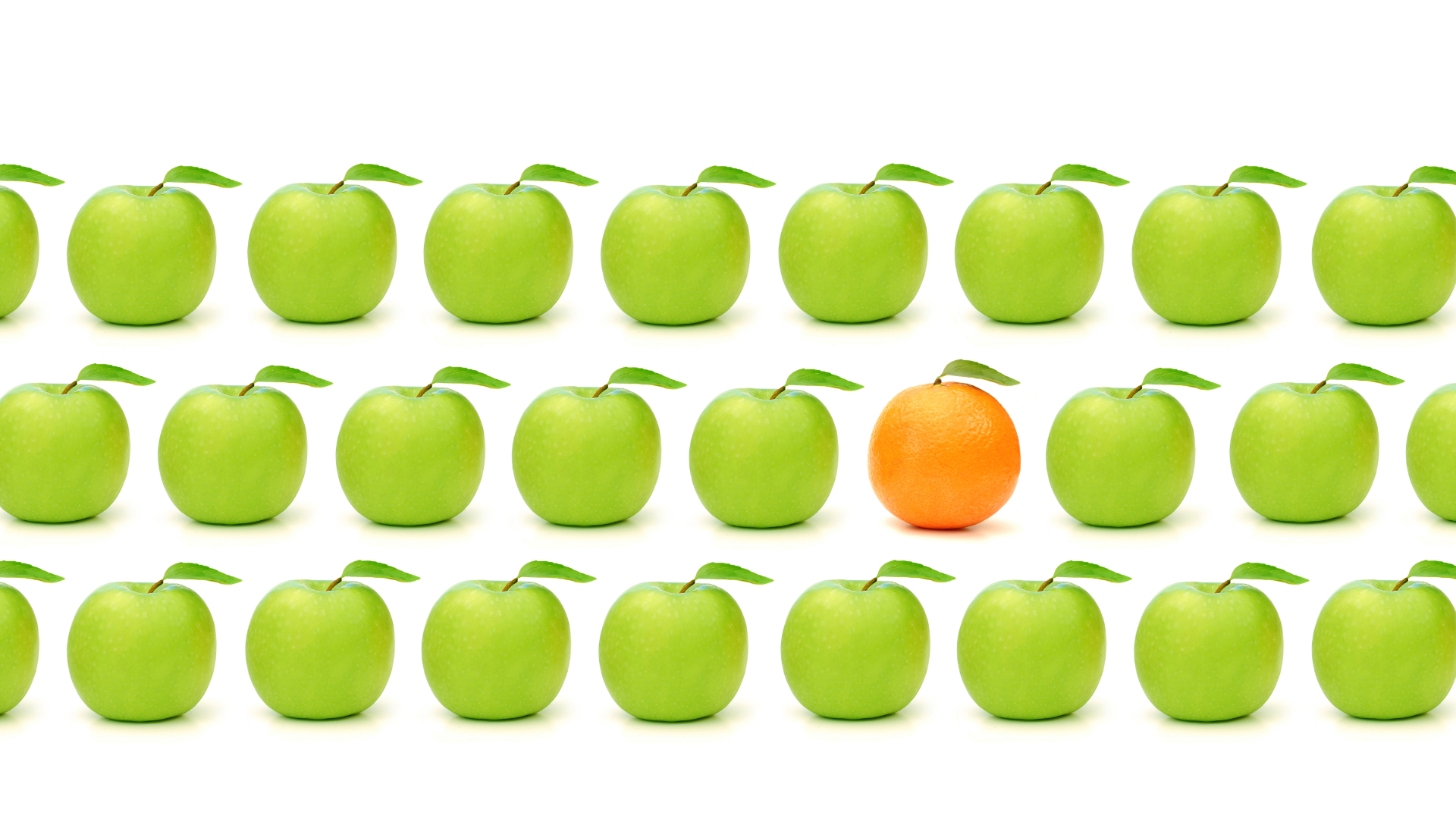 Reihen grüner Äpfel mit einer einzelnen Orange in der Mitte als Sinnbild für eine unverwechselbare Marke.